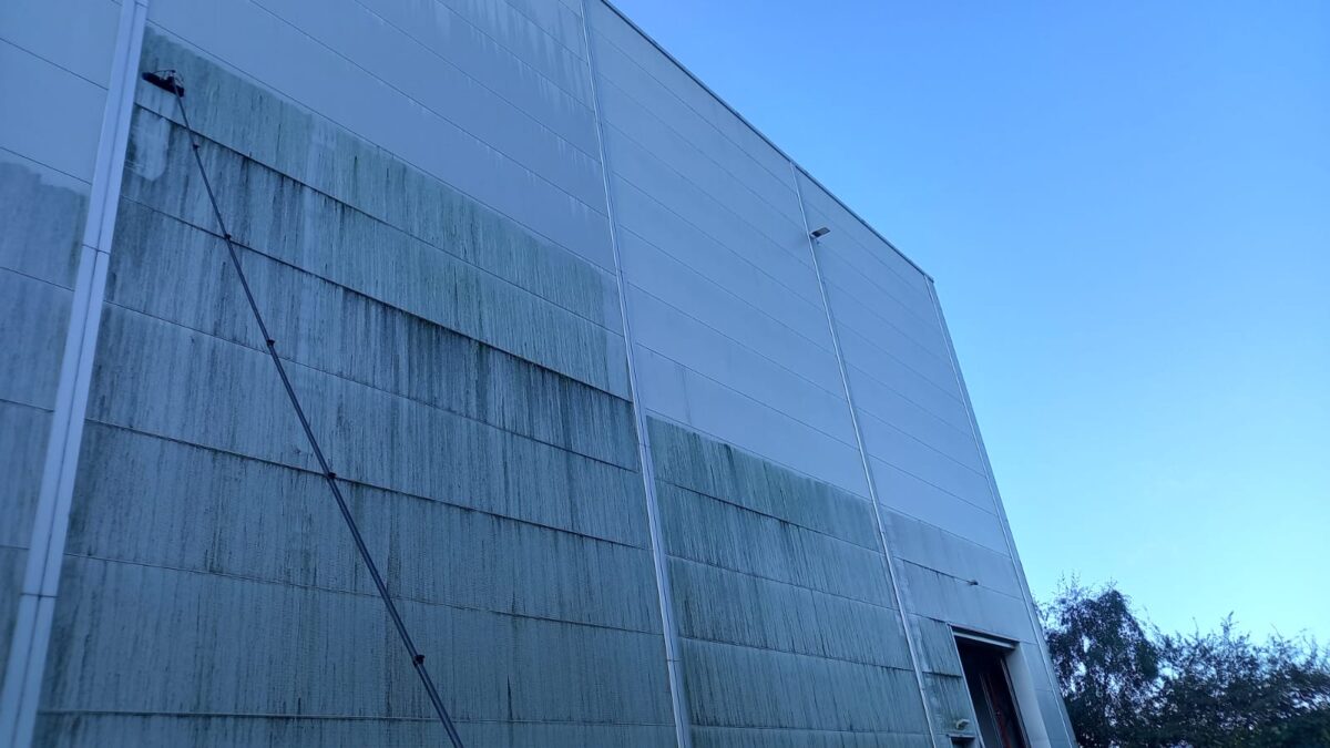 Fassadenreinigung in Ausführung: halb gereinigte Hallenfassade