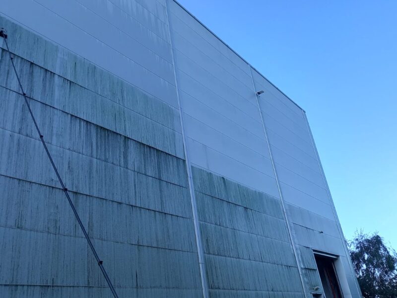 Fassadenreinigung in Ausführung: halb gereinigte Hallenfassade